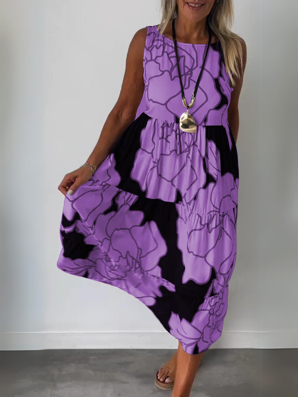 Purple - A woman wearing a sleeveless, tiered midi dress featuring a large-scale black and white floral outline print with tan accents, styled with a gold pendant necklace.