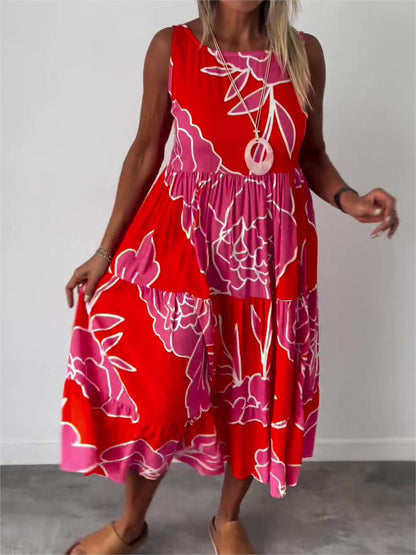 Red - A woman wearing a sleeveless, tiered midi dress featuring a large-scale black and white floral outline print with tan accents, styled with a gold pendant necklace.
