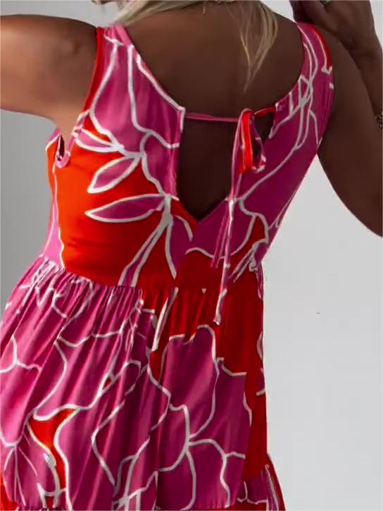 Red - A woman wearing a sleeveless, tiered midi dress featuring a large-scale black and white floral outline print with tan accents, styled with a gold pendant necklace.