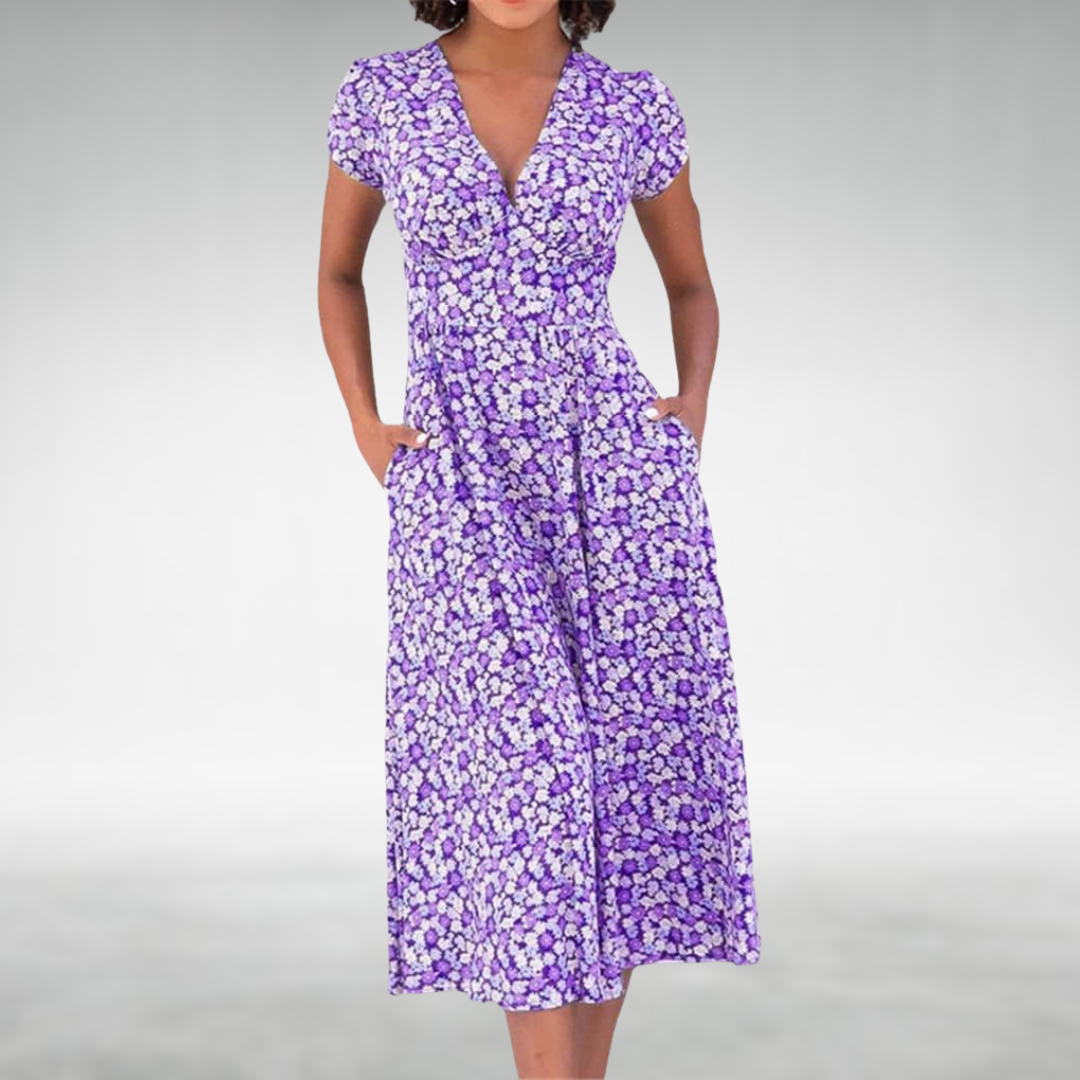 Purple - A woman wearing a blue and white ditsy floral print midi dress featuring a V-neckline, short cap sleeves, and side pockets, set against a neutral gray background.