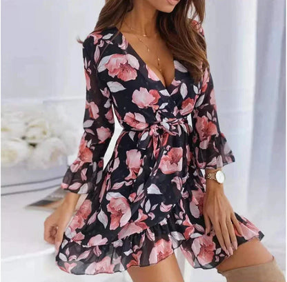 Black - Woman wearing a white chiffon mini dress with pink floral print, featuring a wrap silhouette, ruffled hem, and three-quarter sleeves with ruffled cuffs.