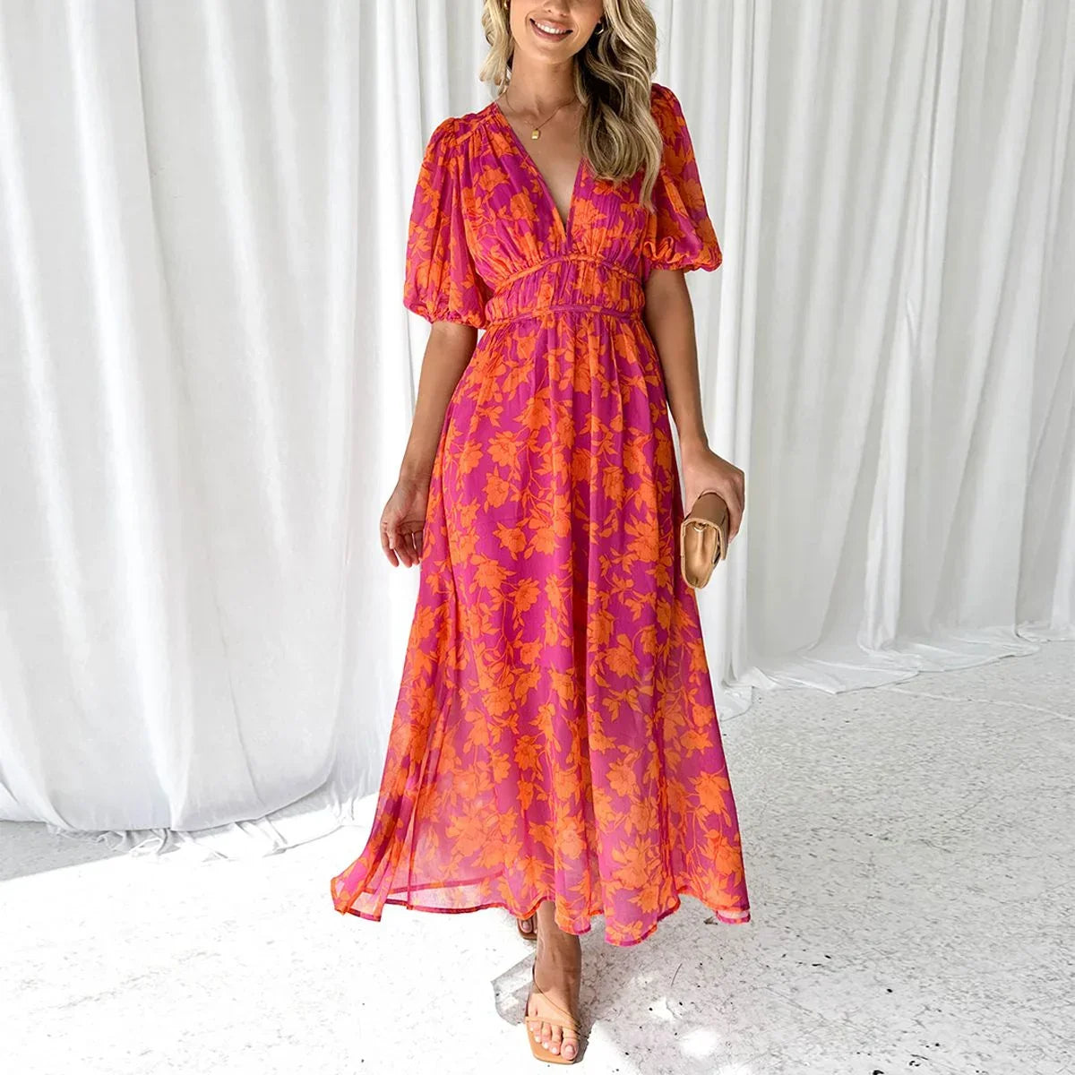 Bright pink and orange floral print midi dress featuring a deep V-neckline, short puff sleeves, and a wide smocked waistband.