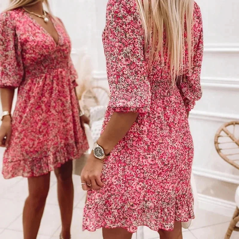 Pink - Woman wearing a pink floral mini dress with a V-neckline and smocked waist.