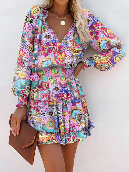 Light Purple - Woman wearing a dark mini dress with large bright floral print, featuring long sleeves, a smocked waist, and a tiered ruffle skirt