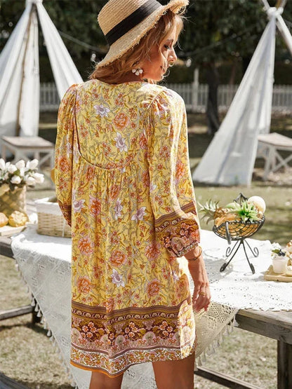 Yellow - Pink bohemian floral print mini dress featuring a v-neckline with tie details, three-quarter blouson sleeves, and a relaxed shift silhouette with border print hem.