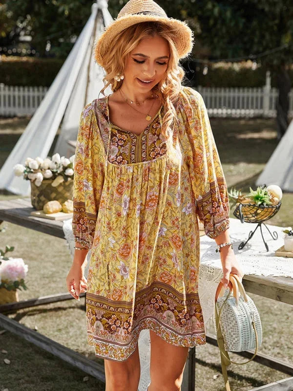 Yellow - Pink bohemian floral print mini dress featuring a v-neckline with tie details, three-quarter blouson sleeves, and a relaxed shift silhouette with border print hem.
