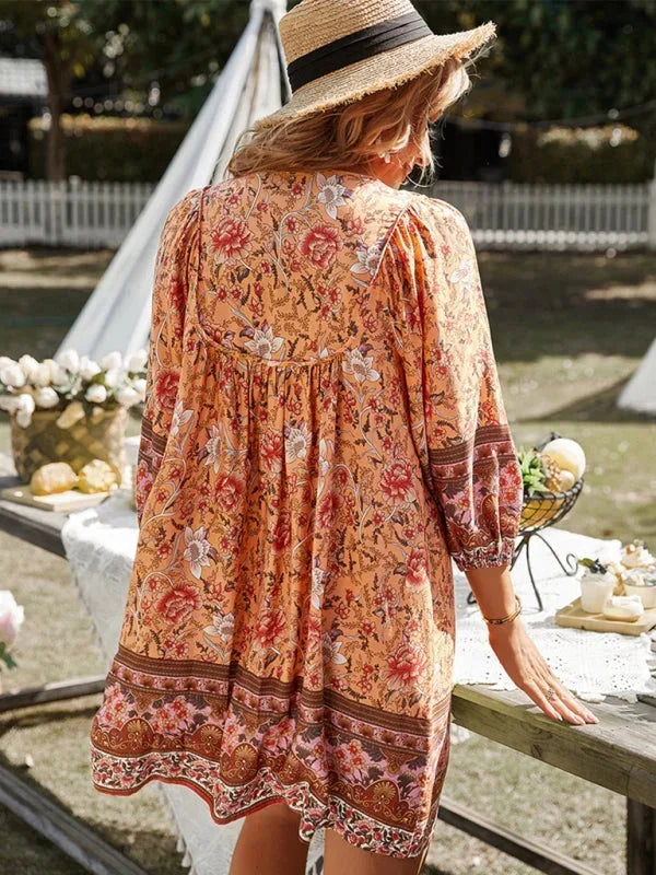Orange - Pink bohemian floral print mini dress featuring a v-neckline with tie details, three-quarter blouson sleeves, and a relaxed shift silhouette with border print hem.