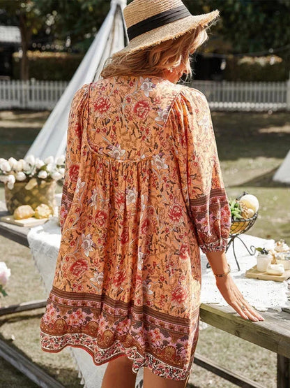 Orange - Pink bohemian floral print mini dress featuring a v-neckline with tie details, three-quarter blouson sleeves, and a relaxed shift silhouette with border print hem.
