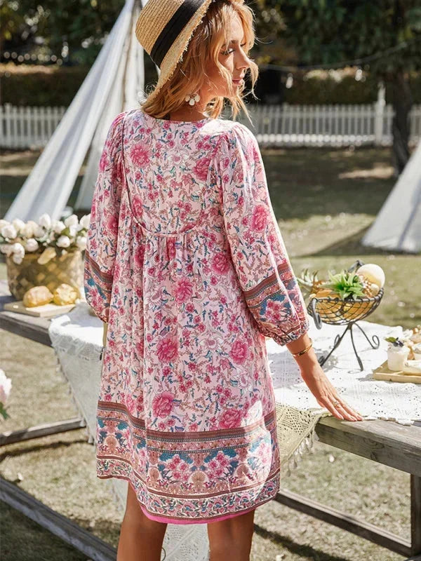Pink - Pink bohemian floral print mini dress featuring a v-neckline with tie details, three-quarter blouson sleeves, and a relaxed shift silhouette with border print hem.