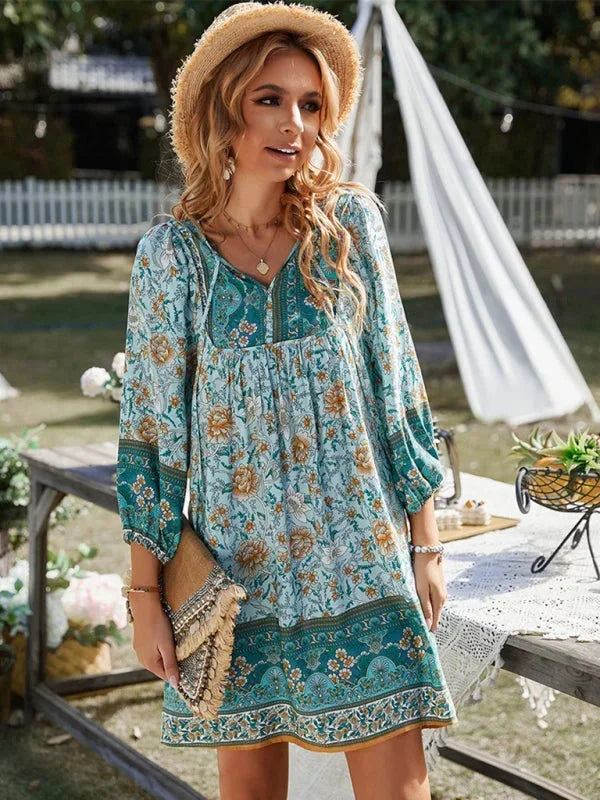 Blue - Pink bohemian floral print mini dress featuring a v-neckline with tie details, three-quarter blouson sleeves, and a relaxed shift silhouette with border print hem.