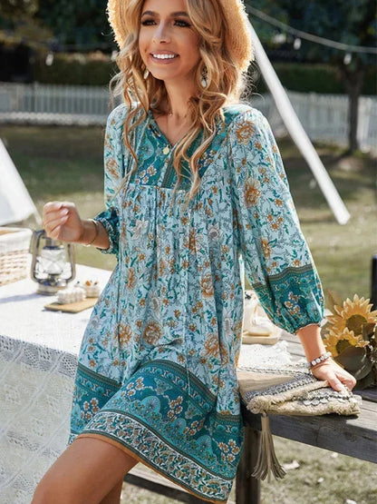 Blue - Pink bohemian floral print mini dress featuring a v-neckline with tie details, three-quarter blouson sleeves, and a relaxed shift silhouette with border print hem.