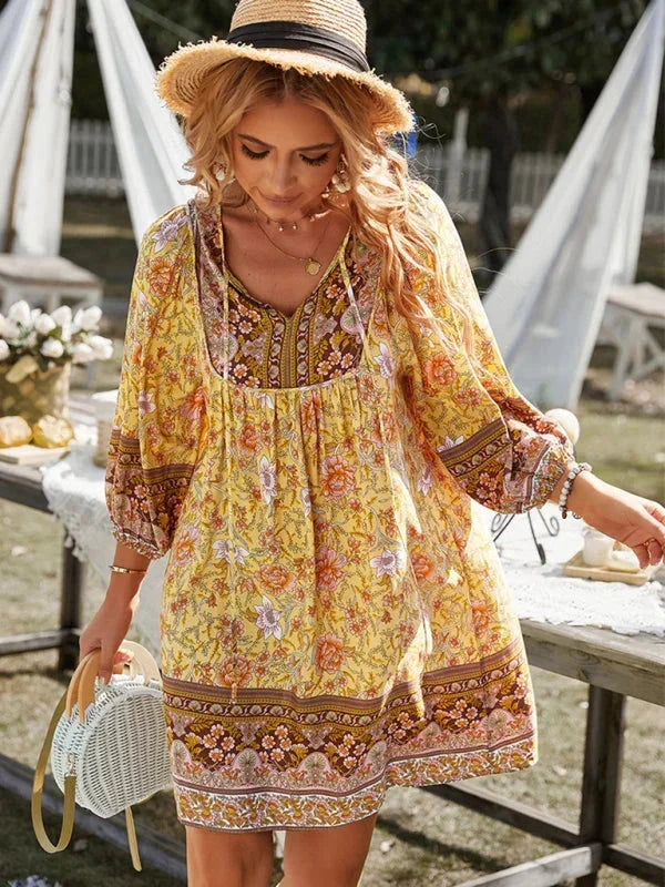 Yellow - Pink bohemian floral print mini dress featuring a v-neckline with tie details, three-quarter blouson sleeves, and a relaxed shift silhouette with border print hem.
