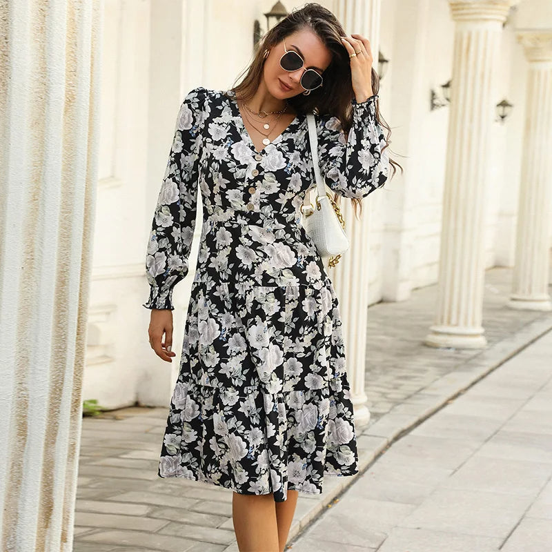 Black - Woman wearing a monochrome large-scale floral print midi dress featuring a V-neckline, button-front bodice, long sleeves, and a tiered skirt.