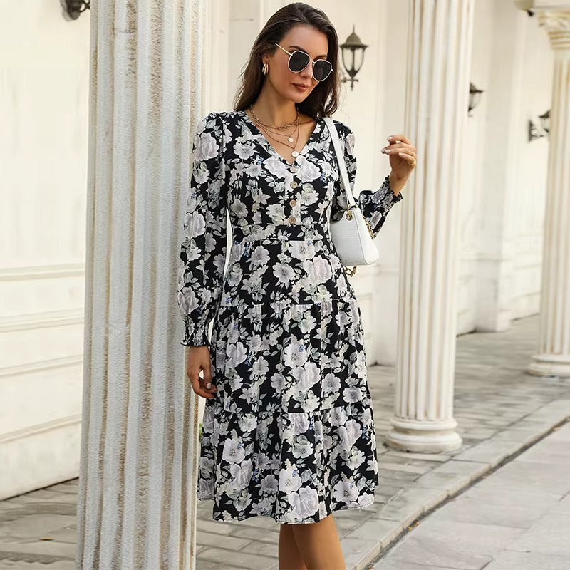 Black - Woman wearing a monochrome large-scale floral print midi dress featuring a V-neckline, button-front bodice, long sleeves, and a tiered skirt.