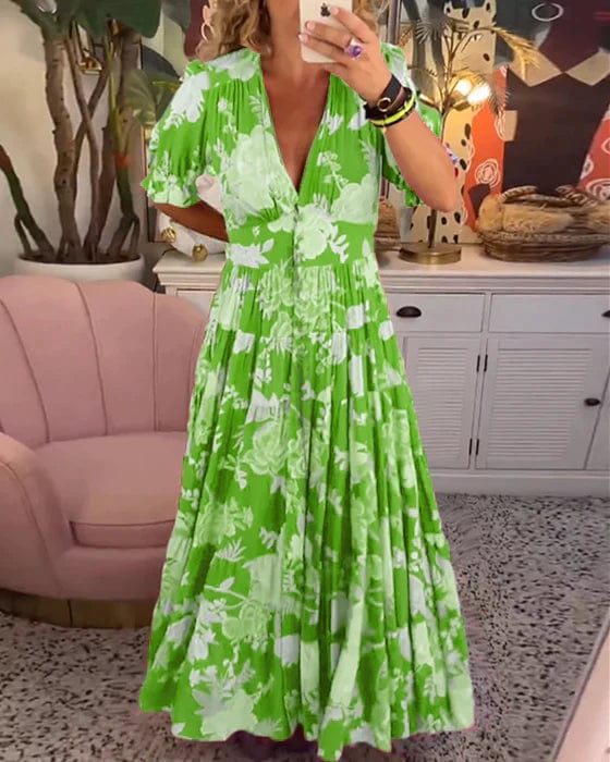 Green - A woman wearing a vibrant pink maxi dress with a blue and light pink floral print, featuring a deep V-neckline, short puff sleeves, and a gathered, flowing skirt.