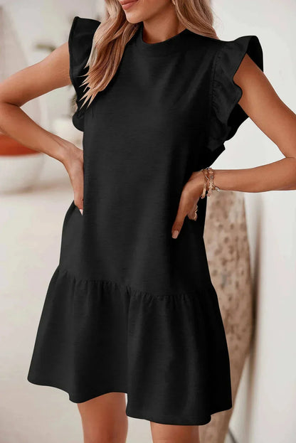 Black textured mini dress featuring flutter sleeves, a high neckline, and a drop-waist ruffled hem.