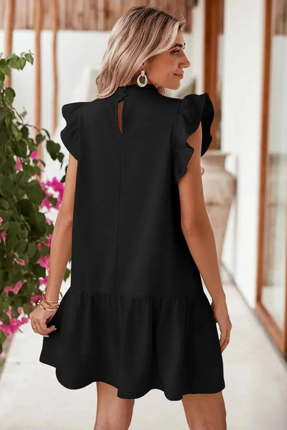 Black - Black textured mini dress featuring flutter sleeves, a high neckline, and a drop-waist ruffled hem.