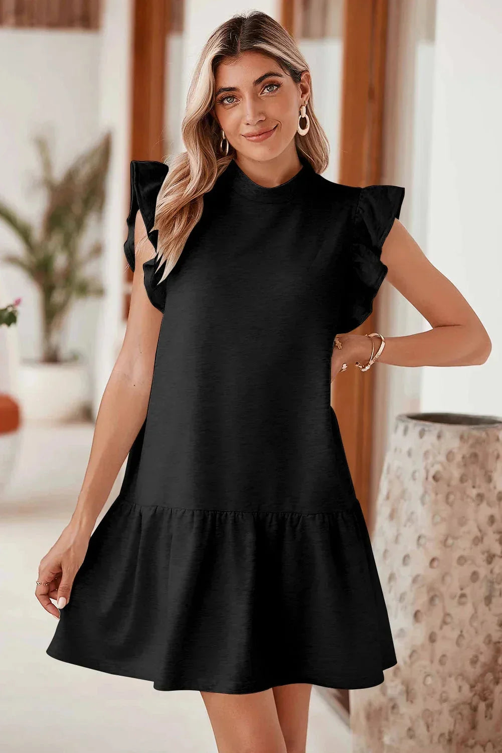 Black - Black textured mini dress featuring flutter sleeves, a high neckline, and a drop-waist ruffled hem.