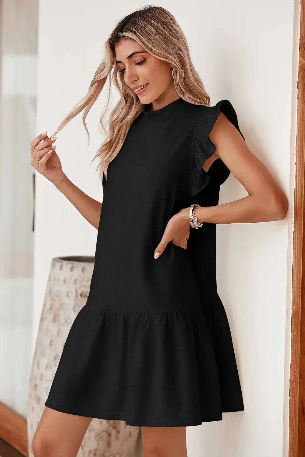 Black - Black textured mini dress featuring flutter sleeves, a high neckline, and a drop-waist ruffled hem.