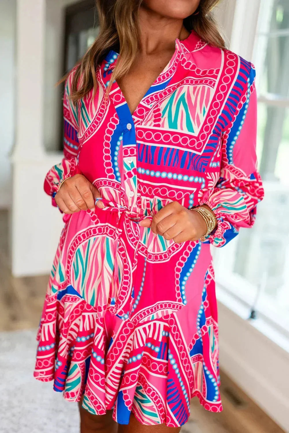Pink - Bright pink and blue geometric scarf print mini dress featuring a collared v-neckline, long balloon sleeves, a drawstring waist, and a ruffled flounce hem.