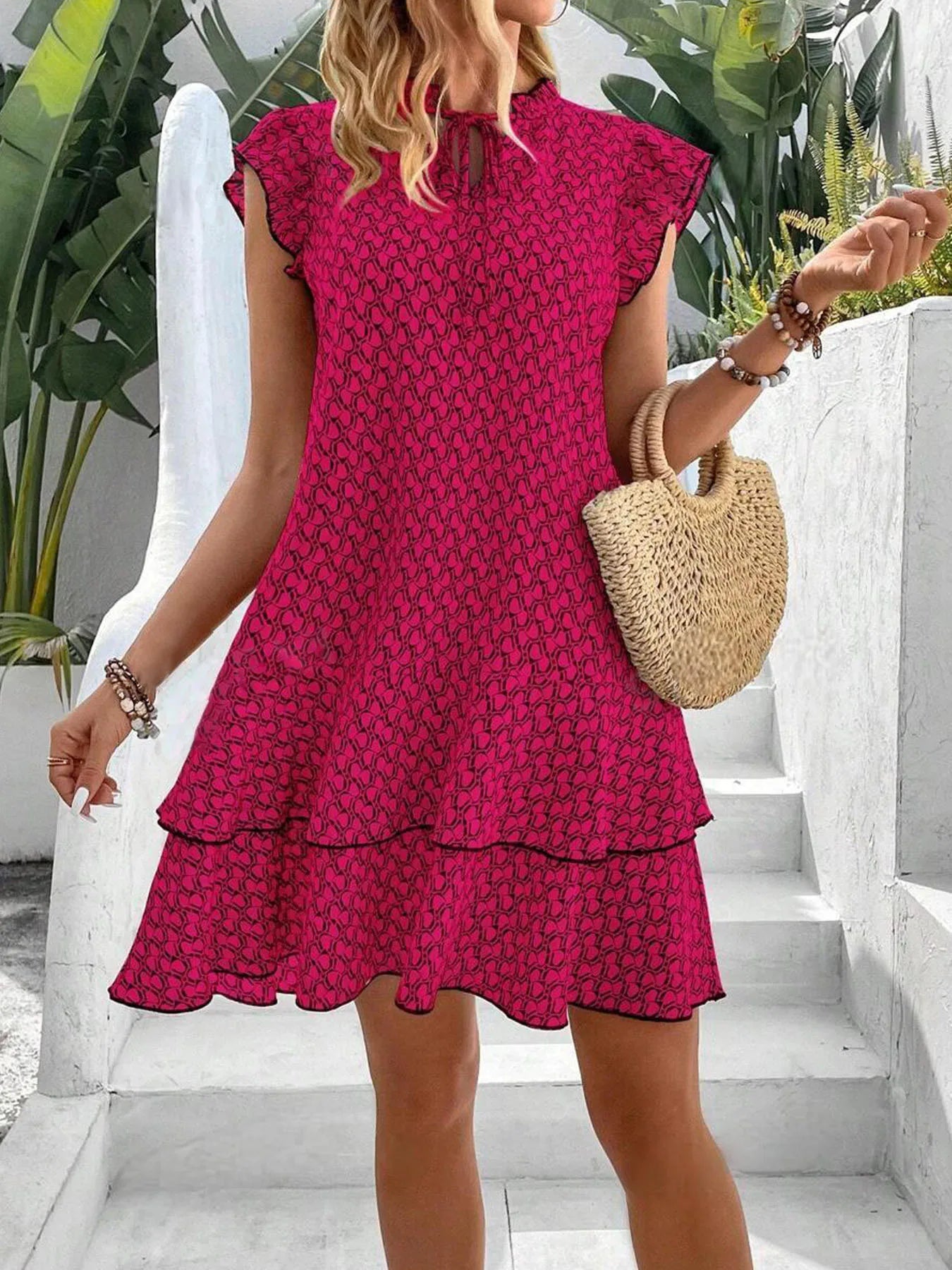 Red - A woman wearing a cream and black geometric print mini dress with flutter cap sleeves, a split neckline, and a tiered ruffle hem with dark contrast piping.