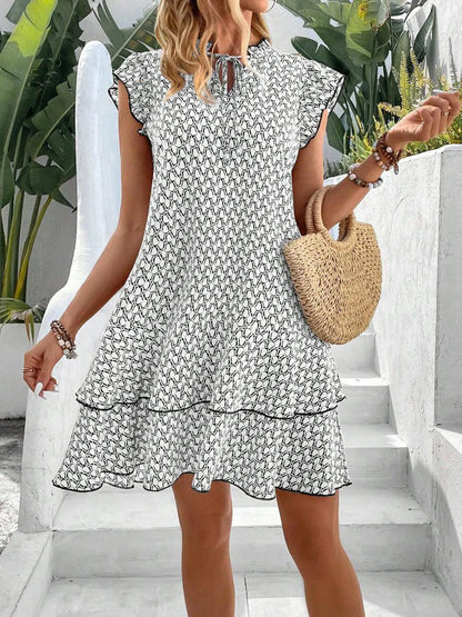 Red - A woman wearing a cream and black geometric print mini dress with flutter cap sleeves, a split neckline, and a tiered ruffle hem with dark contrast piping.