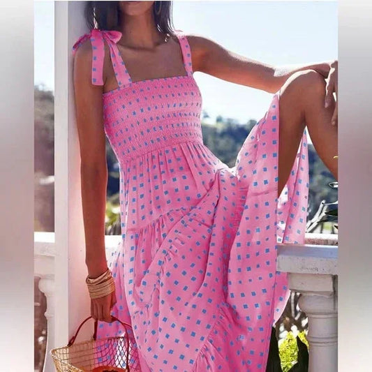 Pink and blue geometric patterned maxi dress featuring a smocked bodice, adjustable tie shoulder straps, and a flowing tiered skirt.