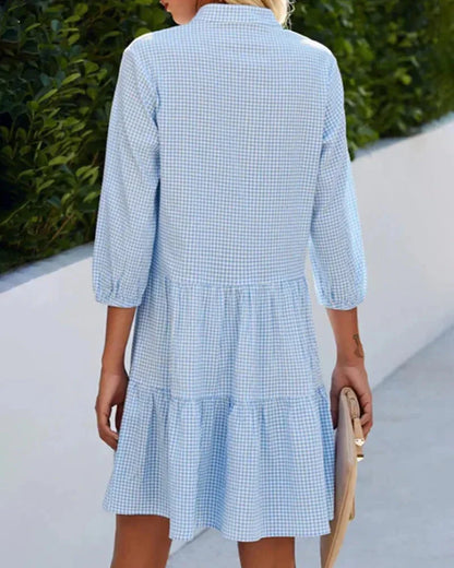 Blue - Light blue and white gingham mini dress featuring a split v-neckline, contrasting button-front closure, three-quarter sleeves, and a voluminous tiered skirt.