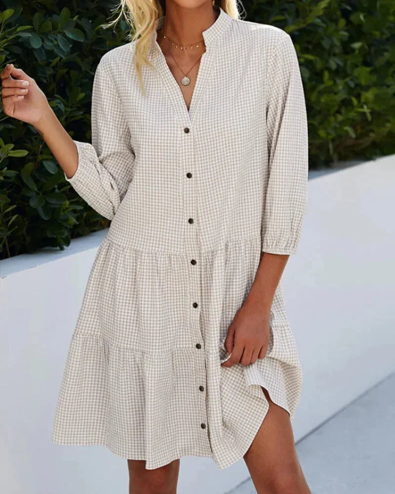 Khaki - Light blue and white gingham mini dress featuring a split v-neckline, contrasting button-front closure, three-quarter sleeves, and a voluminous tiered skirt.