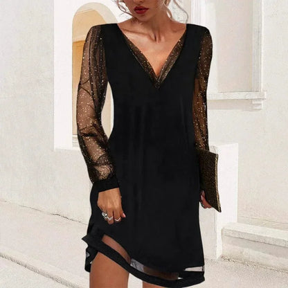 Black mini dress featuring a solid V-neck bodice, long sheer tulle sleeves with metallic glitter flecks, and a sheer panel at the hem.