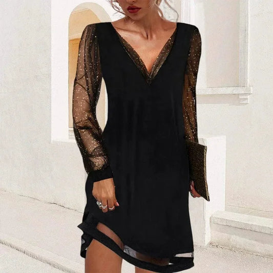 Black mini dress featuring a solid V-neck bodice, long sheer tulle sleeves with metallic glitter flecks, and a sheer panel at the hem.