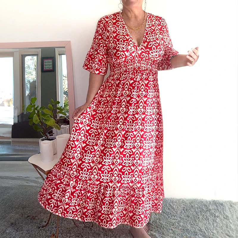 Red - A woman wearing a teal green and white geometric ikat print midi dress with a smocked waist, V-neckline, flutter sleeves, and a tiered hem.