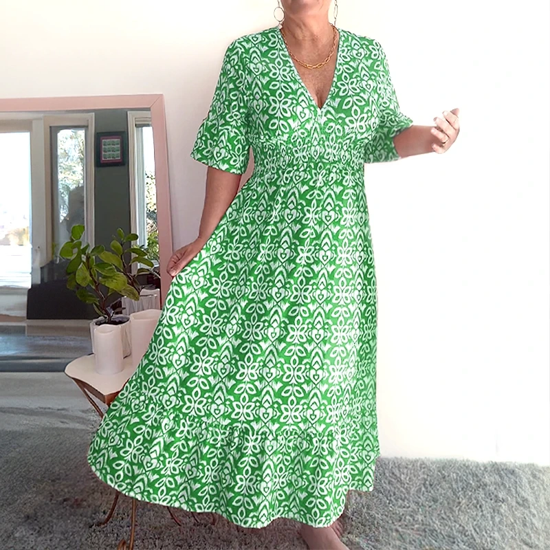 Green - A woman wearing a teal green and white geometric ikat print midi dress with a smocked waist, V-neckline, flutter sleeves, and a tiered hem.