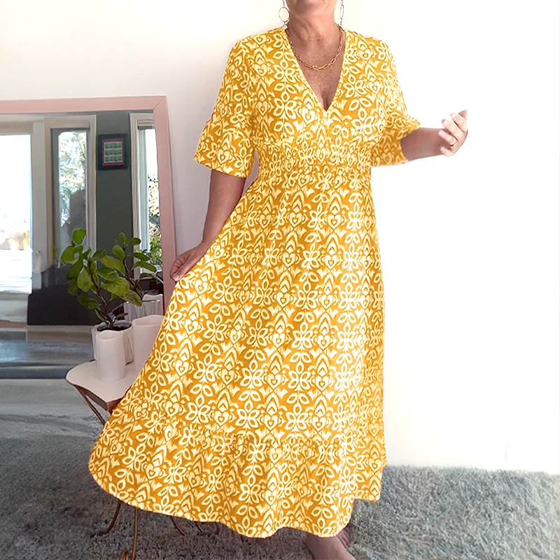 Yellow - A woman wearing a teal green and white geometric ikat print midi dress with a smocked waist, V-neckline, flutter sleeves, and a tiered hem.