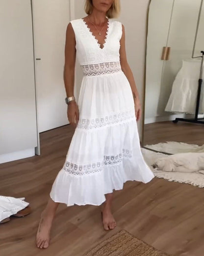 White - A woman wearing a sleeveless white tiered maxi dress with crochet lace inserts at the waist and skirt, featuring a scalloped V-neckline.