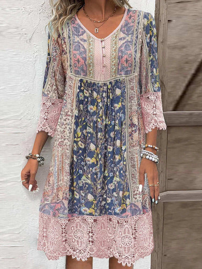 Vintage Floral Rose - A woman wearing a bohemian-style shift dress featuring a mixed floral and paisley print in shades of blue, pink, and cream, detailed with a buttoned henley neckline and wide pink lace trim on the sleeves and hem.