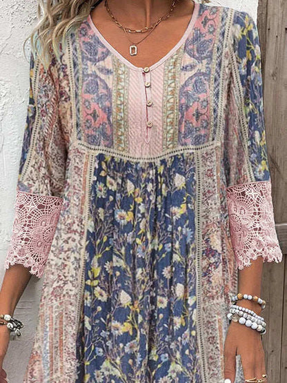 Vintage Floral Rose - A woman wearing a bohemian-style shift dress featuring a mixed floral and paisley print in shades of blue, pink, and cream, detailed with a buttoned henley neckline and wide pink lace trim on the sleeves and hem.