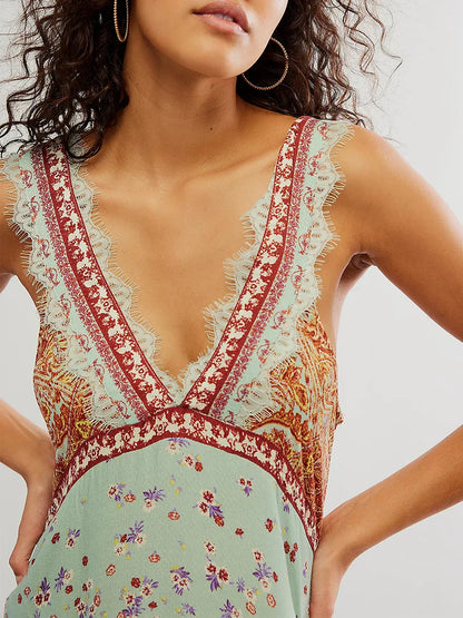 Mint - A woman wearing a sage green bohemian mini slip dress featuring a mixed ditsy floral and rust-colored paisley print, detailed with delicate eyelash lace trim along the V-neckline.