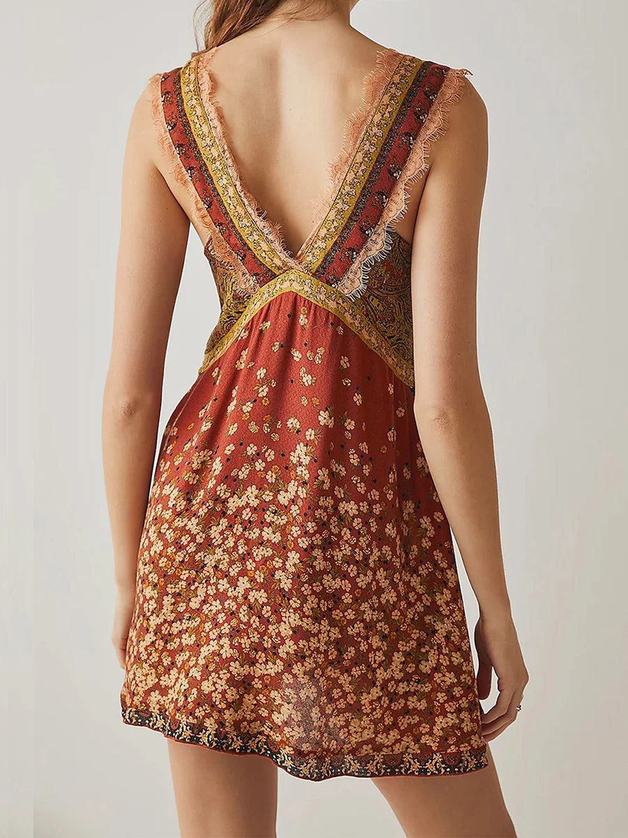 Mint - A woman wearing a sage green bohemian mini slip dress featuring a mixed ditsy floral and rust-colored paisley print, detailed with delicate eyelash lace trim along the V-neckline.