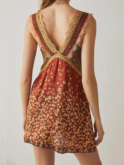 Mint - A woman wearing a sage green bohemian mini slip dress featuring a mixed ditsy floral and rust-colored paisley print, detailed with delicate eyelash lace trim along the V-neckline.