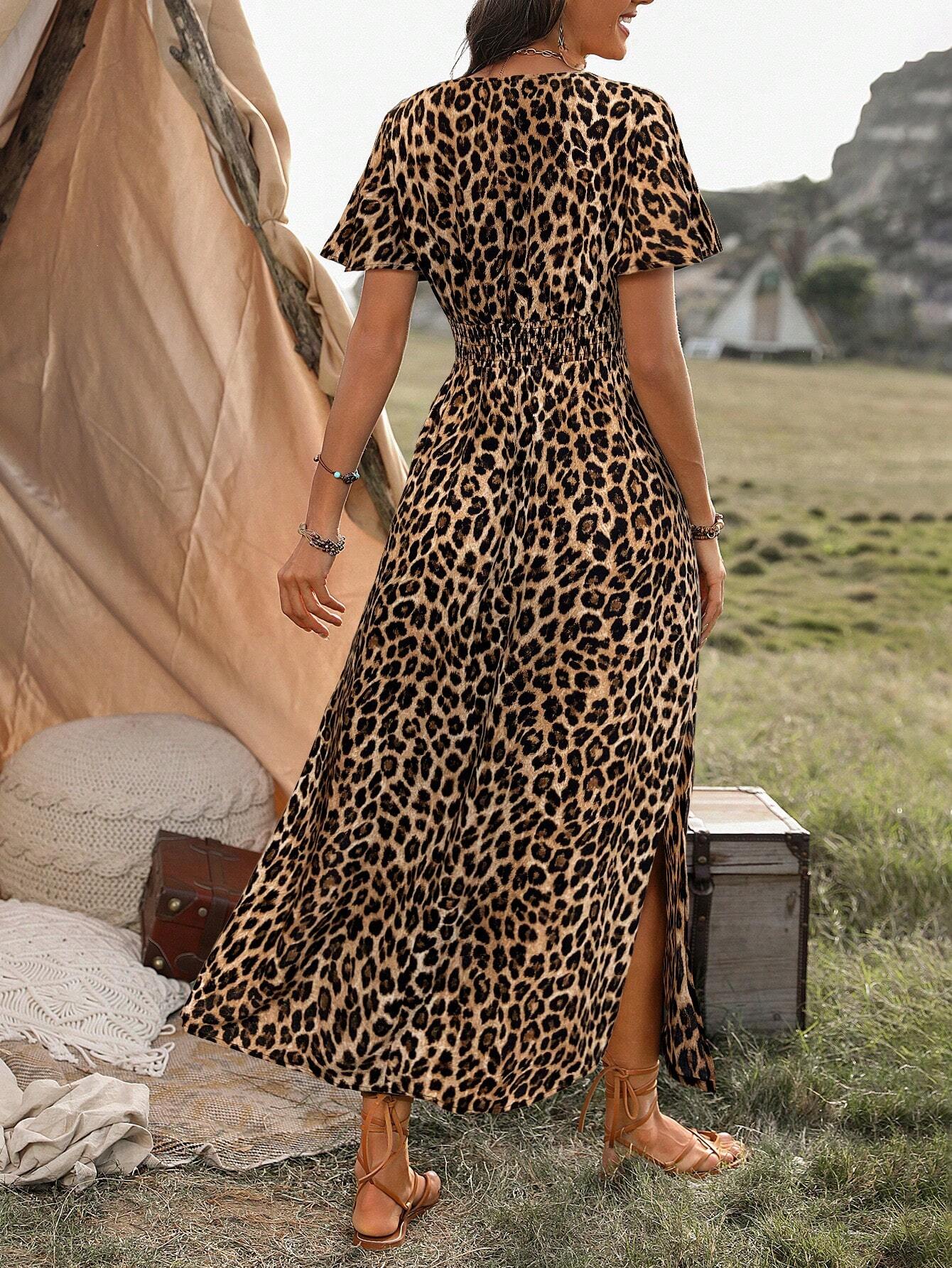 A woman wearing a leopard print maxi dress with a smocked waist, flutter sleeves, and a side slit, holding a woven straw bag in an outdoor setting.