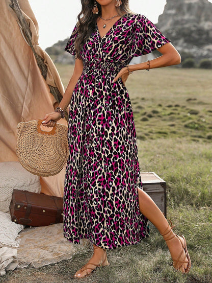 Multicolor - A woman wearing a leopard print maxi dress with a smocked waist, flutter sleeves, and a side slit, holding a woven straw bag in an outdoor setting.
