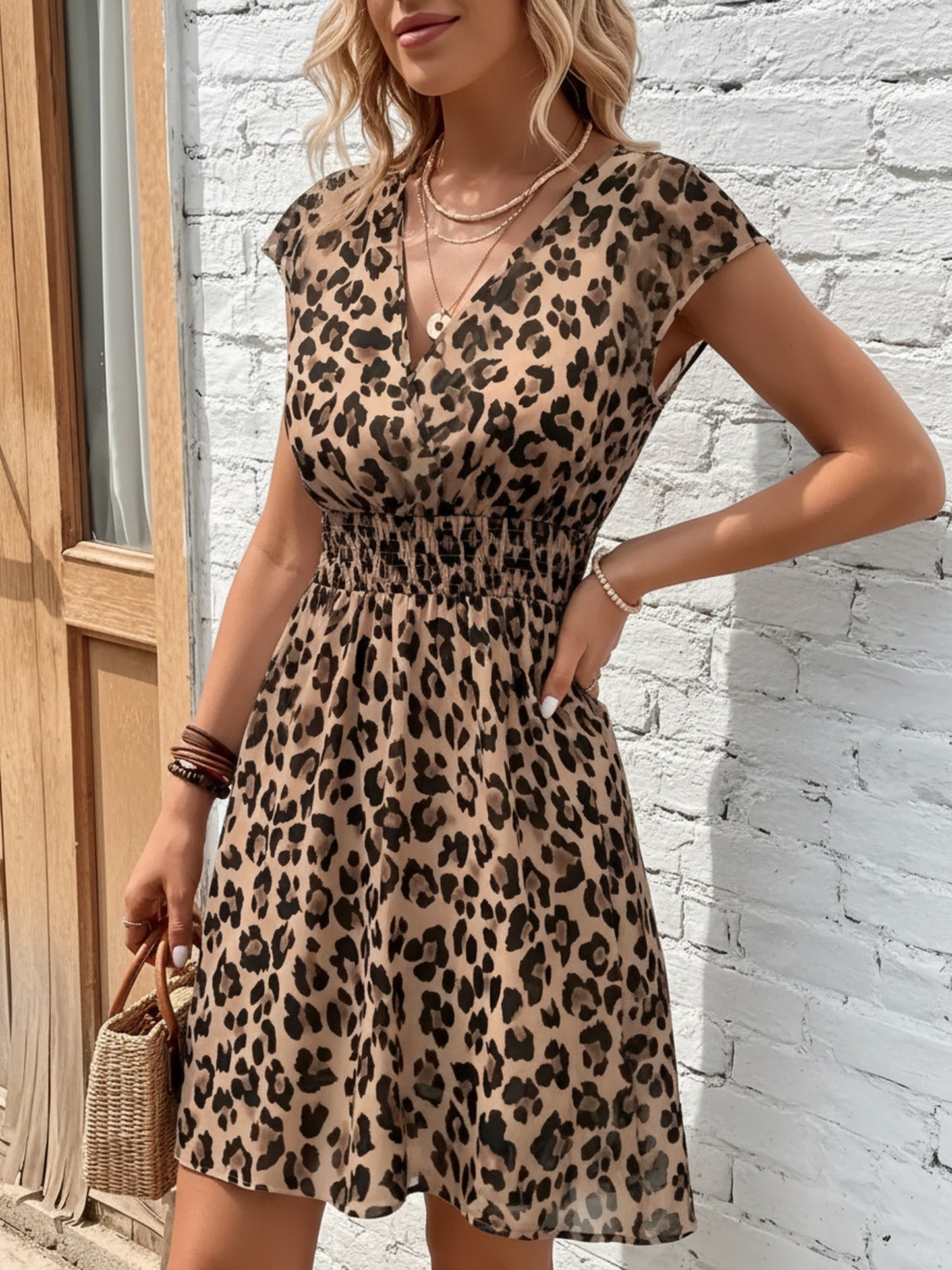 Leopard - Woman wearing a lightweight chiffon mini dress with a leopard print, cap sleeves, and a smocked waist