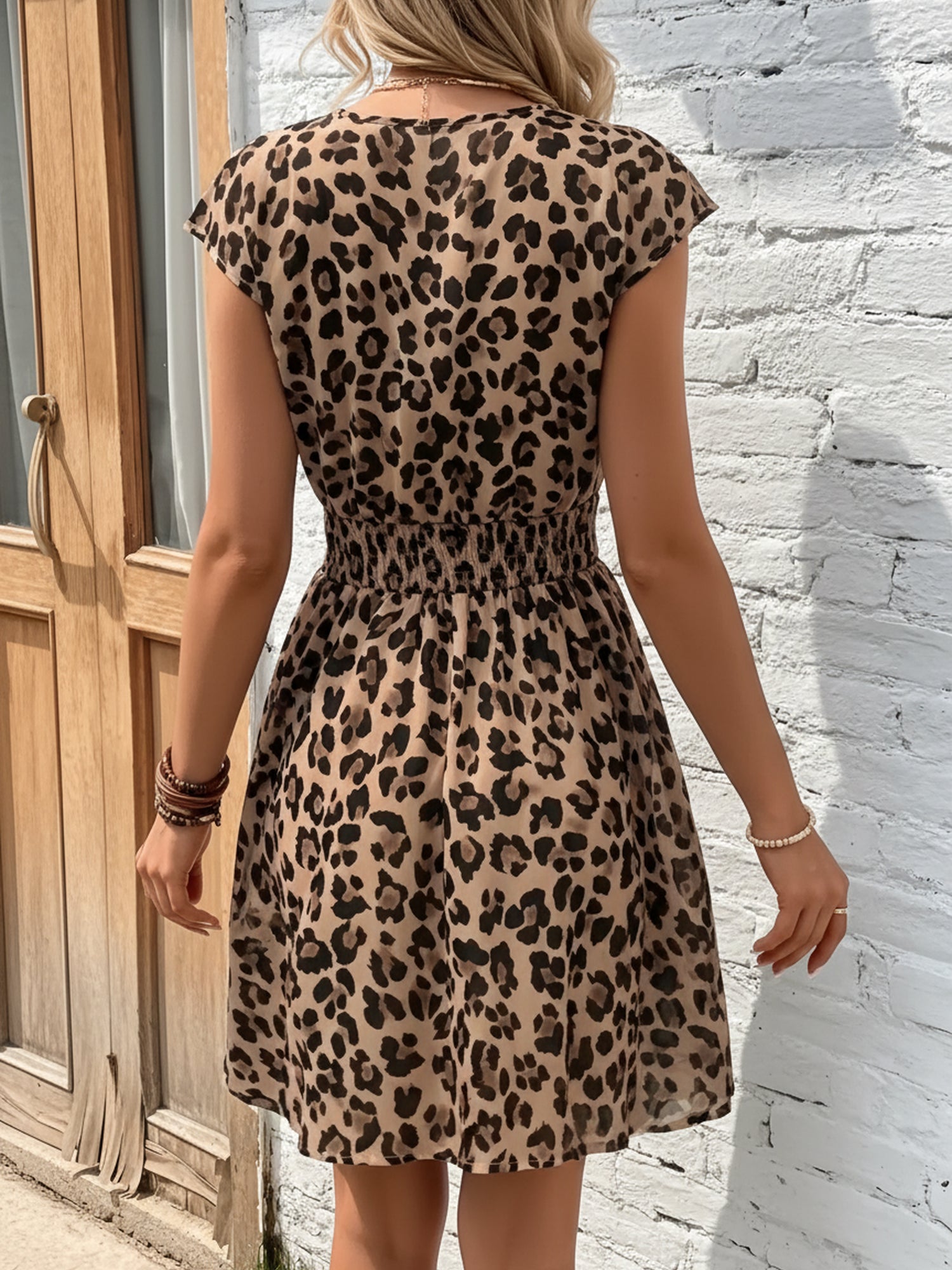 Leopard - Woman wearing a lightweight chiffon mini dress with a leopard print, cap sleeves, and a smocked waist
