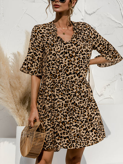Leopard - Woman wearing a lightweight leopard print mini dress with flutter sleeves, a tie neckline, and a tiered skirt.