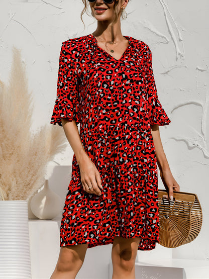 Red - Woman wearing a lightweight leopard print mini dress with flutter sleeves, a tie neckline, and a tiered skirt.