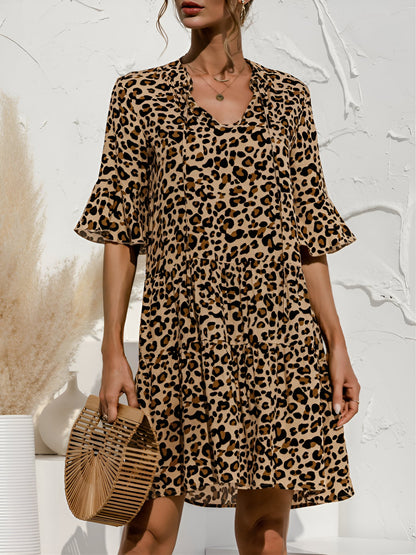 Leopard - Woman wearing a lightweight leopard print mini dress with flutter sleeves, a tie neckline, and a tiered skirt.
