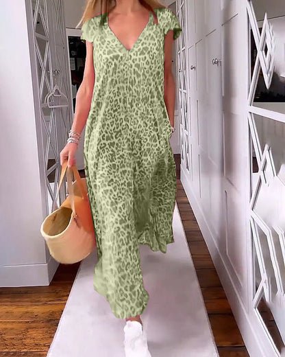 Dark Green - A woman walks down a hallway wearing a pink leopard print maxi dress with a V-neckline and cap sleeves, carrying a woven straw tote bag.