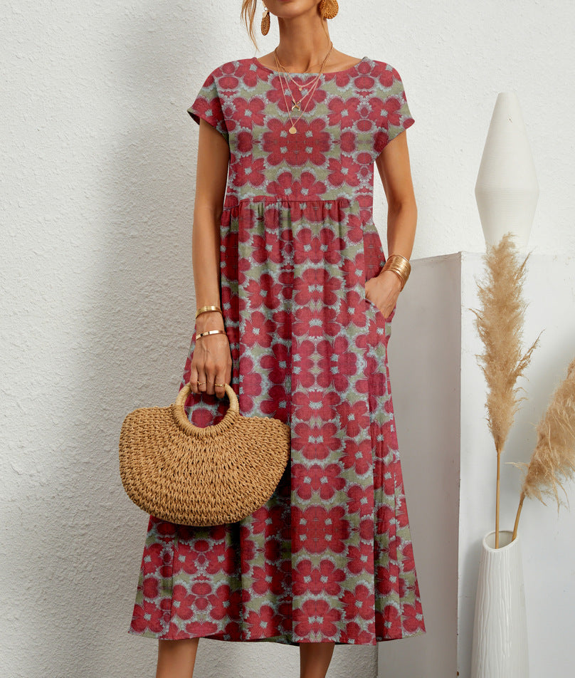 Wine Red & Sage Mosaic - A woman wearing a red and green kaleidoscope floral print linen-blend midi dress with cap sleeves and side pockets, holding a woven straw handbag.