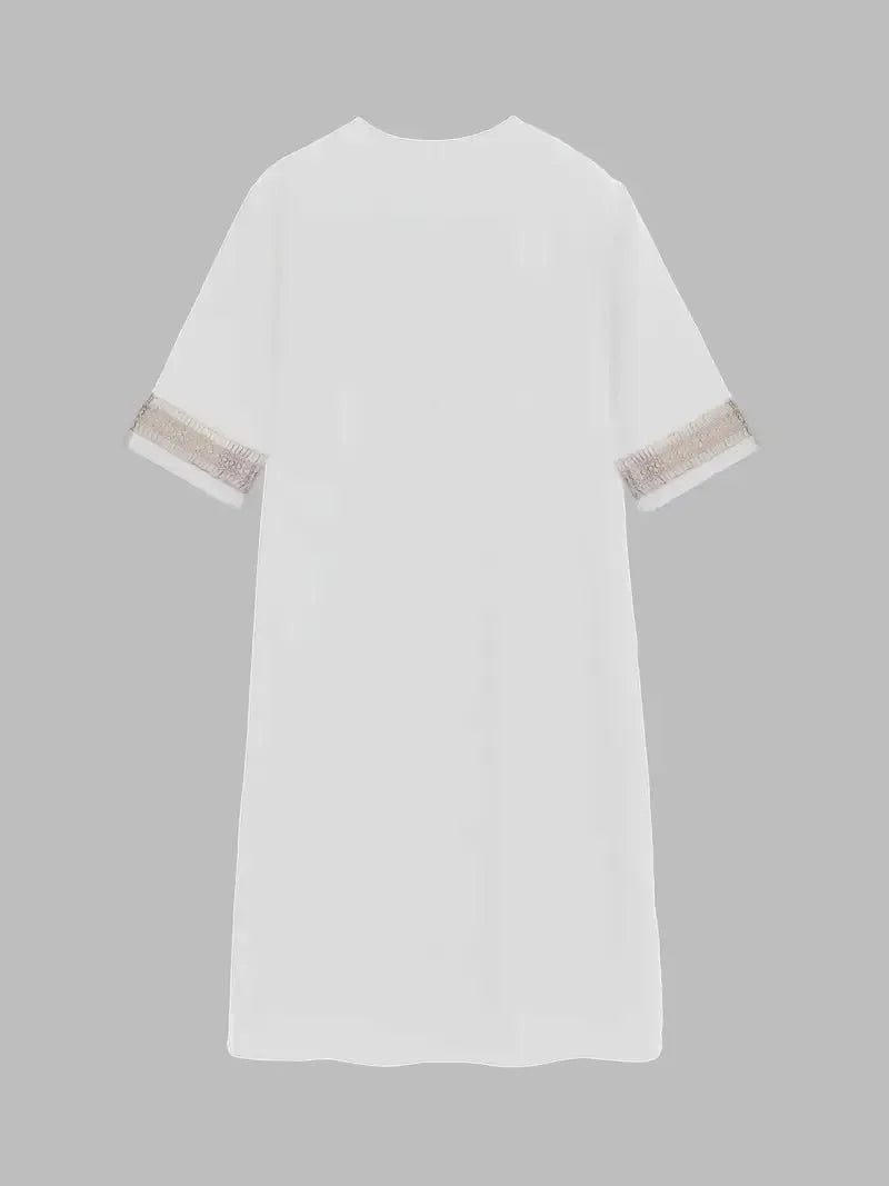 White - A woman wearing a white, knee-length shift dress made of textured linen-like fabric, featuring intricate beige crochet lace trim along the deep V-neckline and elbow-length sleeve cuffs.